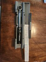 Torque wrench in open grey case with manual