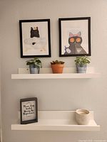 overall view with framed cat prints, faux plants, framed quote, ceramic pot candle