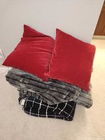 stack showing two red pillows atop two folded blankets