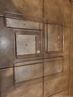 Top view of four clear plastic drawer organizers of varying sizes placed on tiled floor