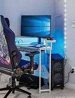 Full view of white metal and glass L-shaped desk situated in corner with monitor on raised shelf