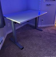 Front view of assembled white adjustable desk showing tabletop, legs and control switch