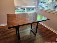 Rectangular wood dining table with metal legs positioned in corner of room