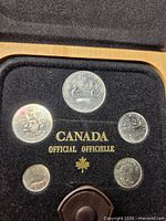 Open presentation case showing five coins and velvet insert