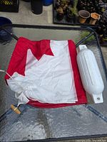 Folded Canada flag with rope and toggle visible; plastic fender present but not part of lot