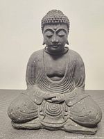 Front view of dark gray stone Buddha statue showing overall design and condition