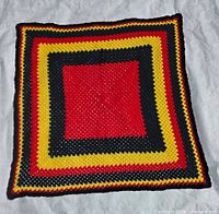 Full view of square crocheted afghan showing colour pattern