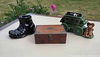 All three items staged together: wood box, black boot vase, green stagecoach figurine