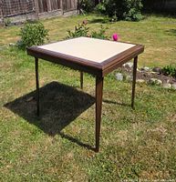 Perspective view of square wood card table on grass