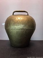 Front view of brass cowbell showing handle and decorative band