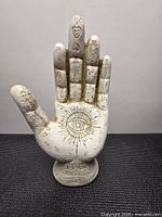 Front view showing eye, sun and palmistry symbols on hand sculpture