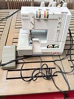 Front view of Elna PRO44DE serger with foot pedal and cords visible