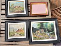 Group view of three framed paintings and one empty frame