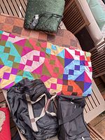 Overview of quilt, heated blanket, and two duffel bags on table
