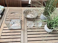 All items grouped on table: silver bowl, glass vase, candleholder, crystal compote, two planters with faux grass