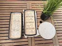 Two rectangular ceramic trays (one divided shown) and one round stoneware piece on table