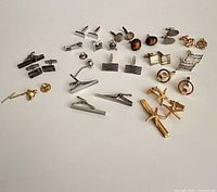 All cufflinks, tie bars and tie tack grouped on flat surface