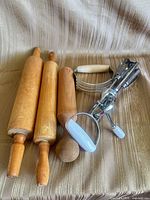 Group shot showing two rolling pins, wooden pestle, Ekco dough blender, rotary egg beater
