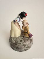 Front view of Snow White bending toward Dopey on cobblestone base