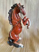 Front view of brown porcelain rearing horse with cord and tassel