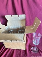 Box containing five stemmed glasses with one glass displayed outside