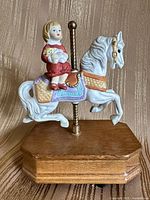 Front view of carousel horse figurine with child rider on wood base