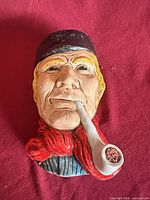 Front view of chalkware seaman plaque showing facial details, pipe, colors