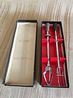 Top view of open box showing two chrome utensils with wood handles