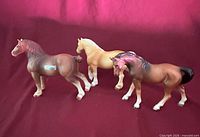 Three porcelain horse figurines standing side by side
