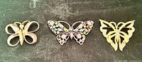 Front view of three butterfly brooches showing designs and colours