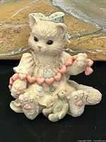 Front view of resin kitten figurine showing heart garland, teddy bear, dress details