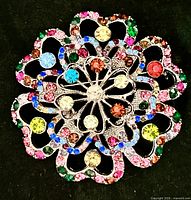 front view of silver-tone brooch showing multicolor rhinestones and floral openwork design