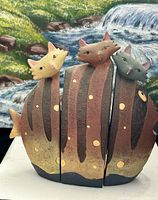 Front view of three interlocking ceramic cat figurines showing color and design