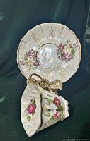 Saucer upright behind teacup showing floral design, lustre finish and gold trim