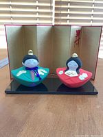 Front view of dolls on base with folding screen