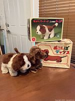 Both plush dogs displayed in front of their original boxes on table
