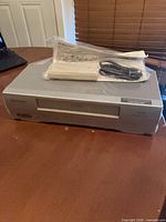 Front and top view of Emerson EWV404 VCR with remote, cord and manual