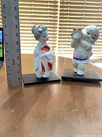 Both Hakata figurines on stands with ruler for height reference
