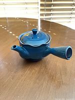 Side view of blue/teal ceramic Kyusu teapot with side handle and lid