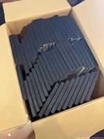 Open cardboard box containing numerous black DVD cases