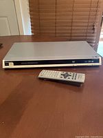 Front and top view of Panasonic DVD-S26 player with remote placed in front