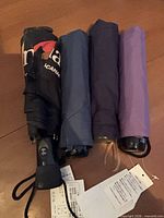 Four folded umbrellas side by side showing colors and handles