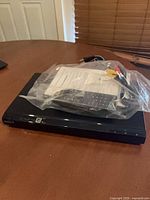 Player with bagged remote, cables, paperwork on top