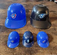Group of five helmets, showing team logos and colors