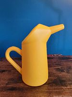Side view of yellow plastic batter dispenser showing handle and angled spout
