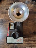 Front view of Imperial Debonair camera with attached flash showing lens, shutter button, grid panel and branding