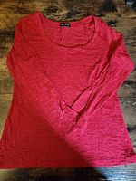 Full view of red long sleeve shirt laid flat
