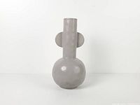 front view of matte gray ceramic vase showing bulbous base, tall neck, and ribbed side handles