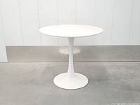 Full view of white tulip dining table showing pedestal base and round top