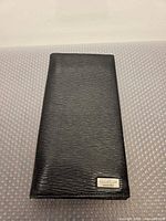 Front view of black leather wallet with metal logo plate